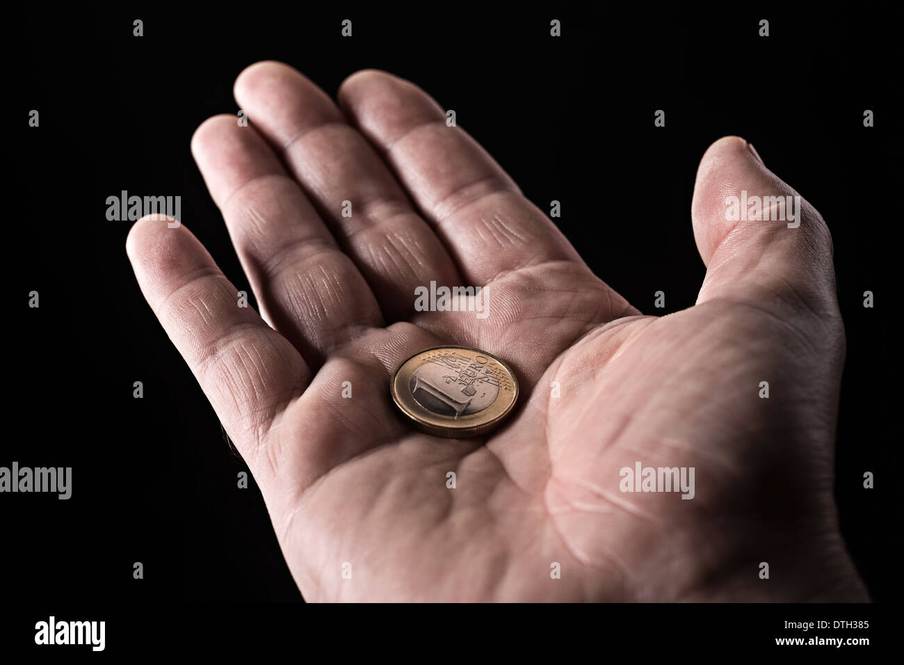 Mano de un hombre mayor con una moneda de euro en la palma de la mano. Foto de stock