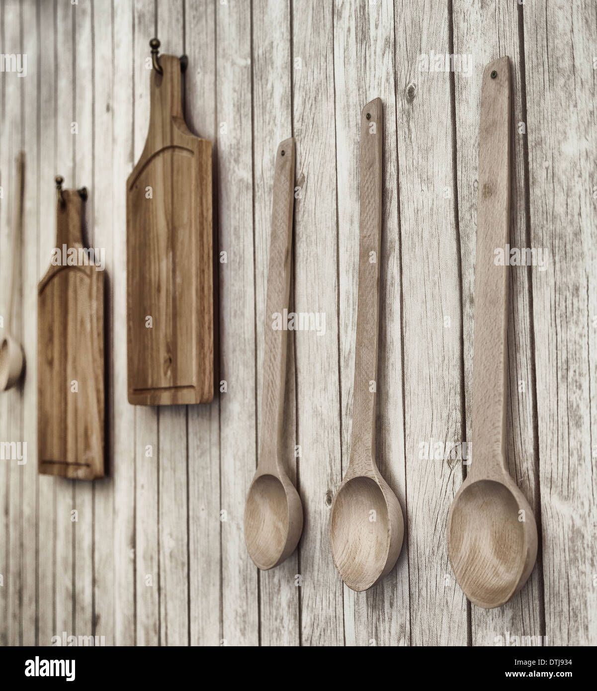 Vintage foto estilizada de tablas de cortar y cucharas de madera colgadas en la pared, utensilios de cocina Foto de stock