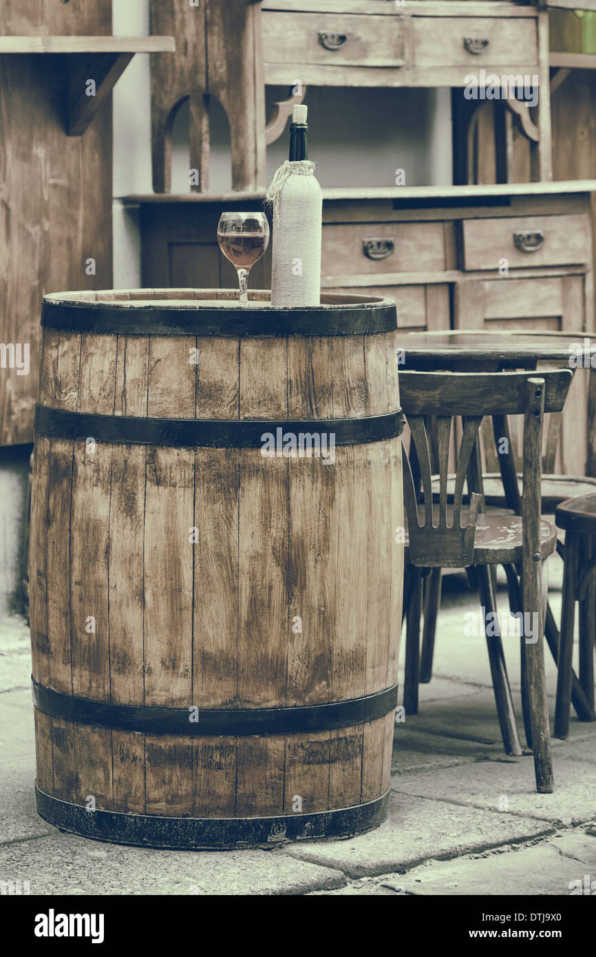 Vintage foto estilizada de barril de madera con botellas de vino y cristal,  silla y mesa de café al aire libre Fotografía de stock - Alamy