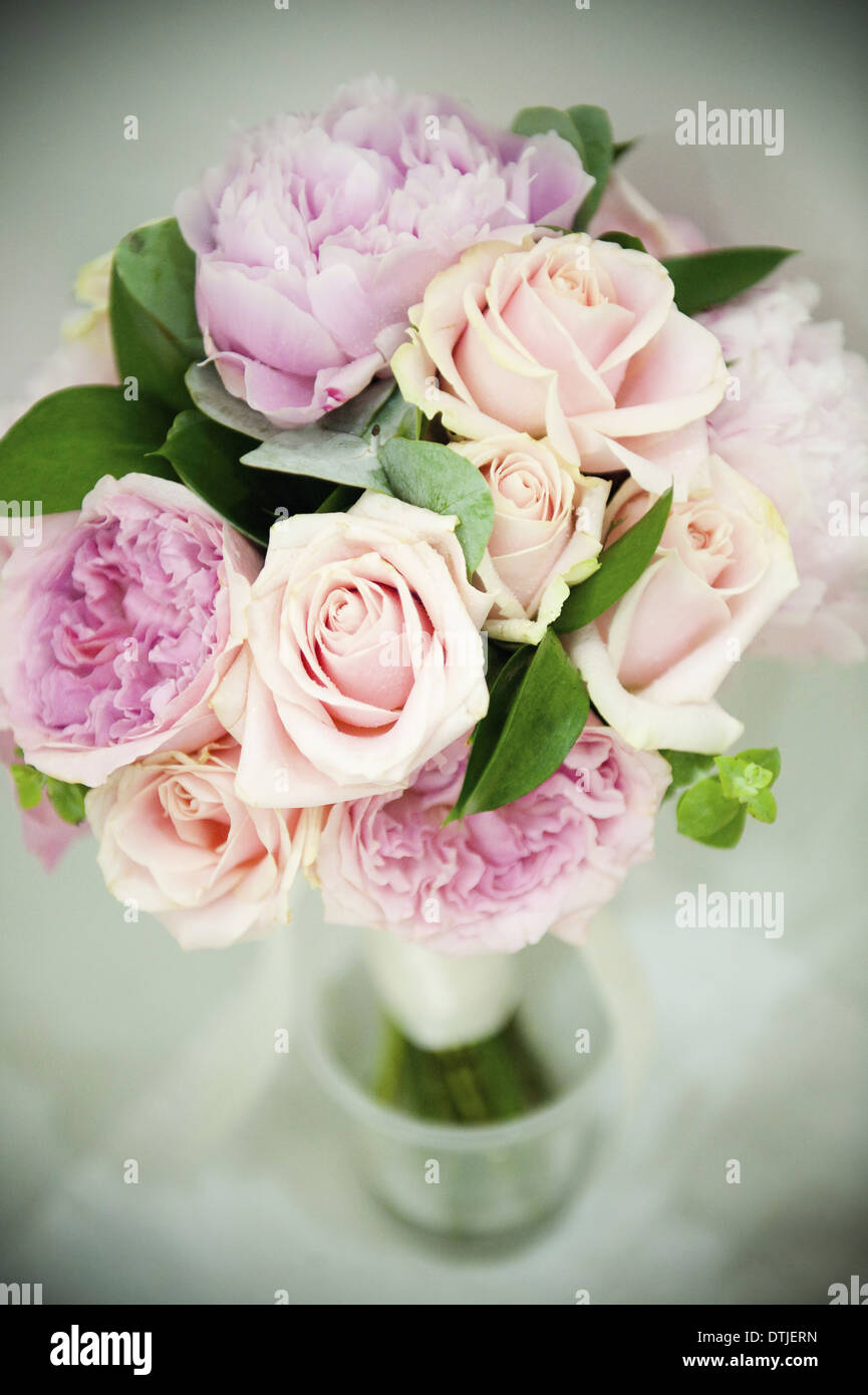 Un ramo de rosas color rosa pastel y lavanda pálido peonías con pequeñas hojas verdes de Inglaterra Foto de stock