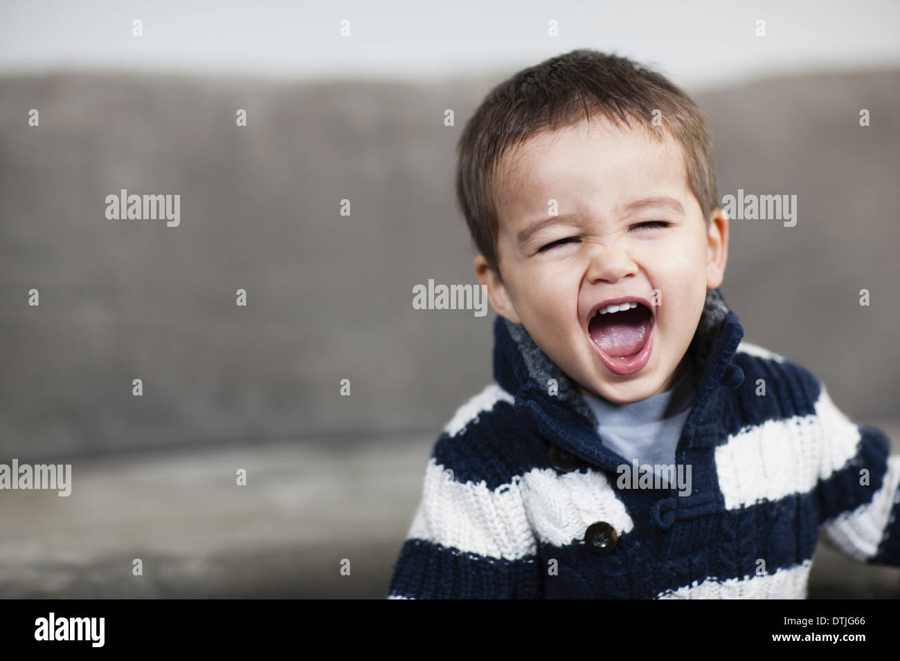 Un muchacho en una camisa a rayas abriendo su boca amplia Pennsylvania, EE.UU. Foto de stock