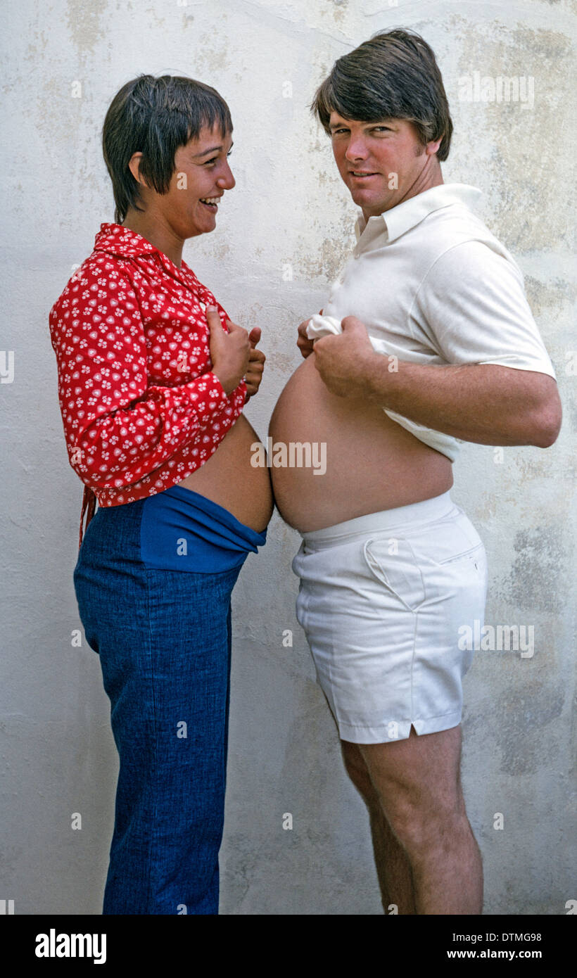 Un joven hombre potbellied y su esposa embarazada divertirse comparando sus estómagos protuberantes antes del nacimiento del bebé, en el sur de California, Estados Unidos. Foto de stock