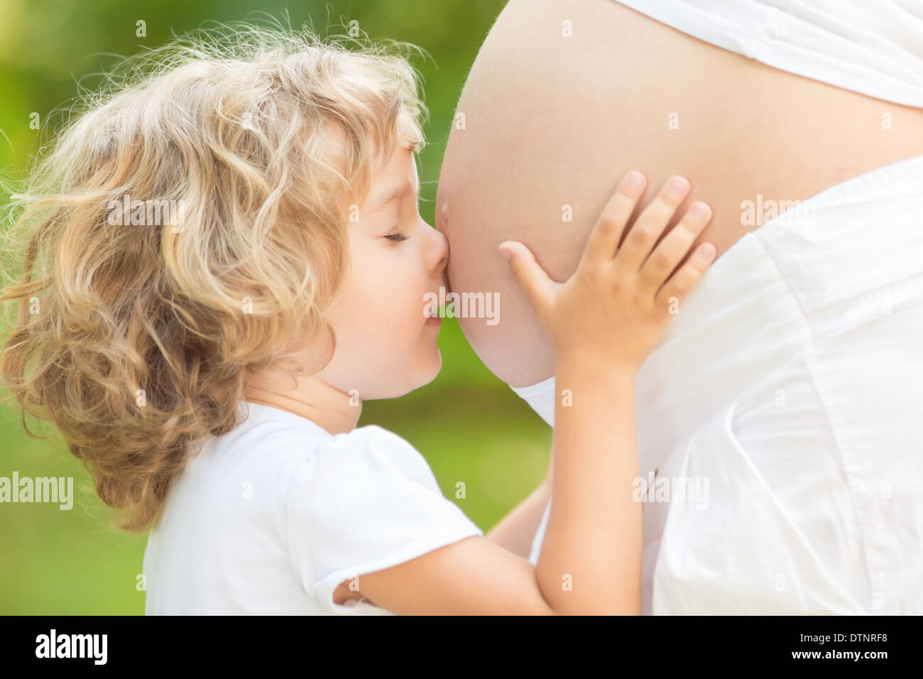 Niño besar el vientre de la mujer embarazada Foto de stock