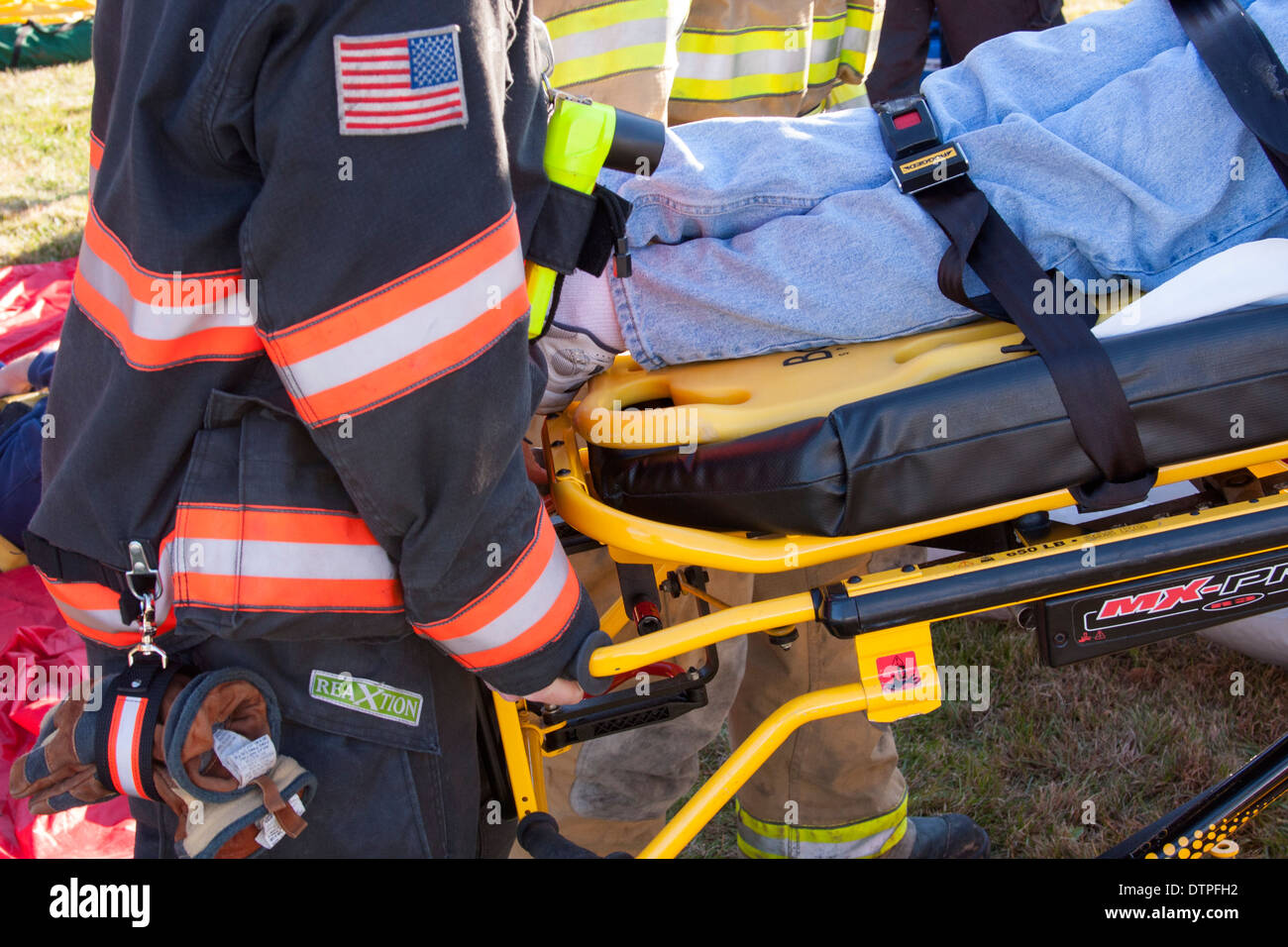 Los técnicos médicos de urgencias técnicos sanitarios y bomberos, ayudar a un paciente en una camilla Foto de stock