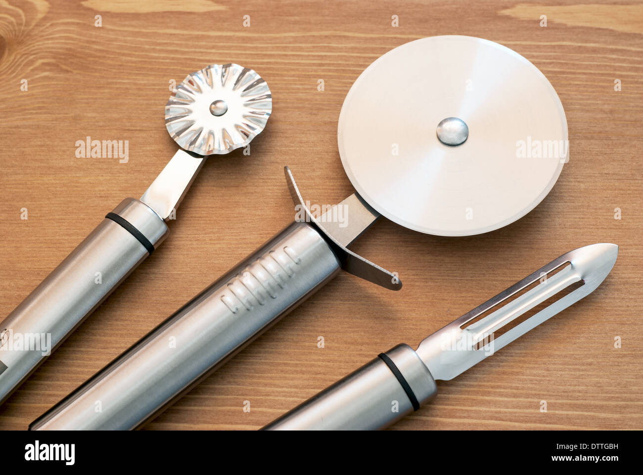 Conjunto de nuevas herramientas de cocina de acero inoxidable sobre fondo de madera. Foto de stock