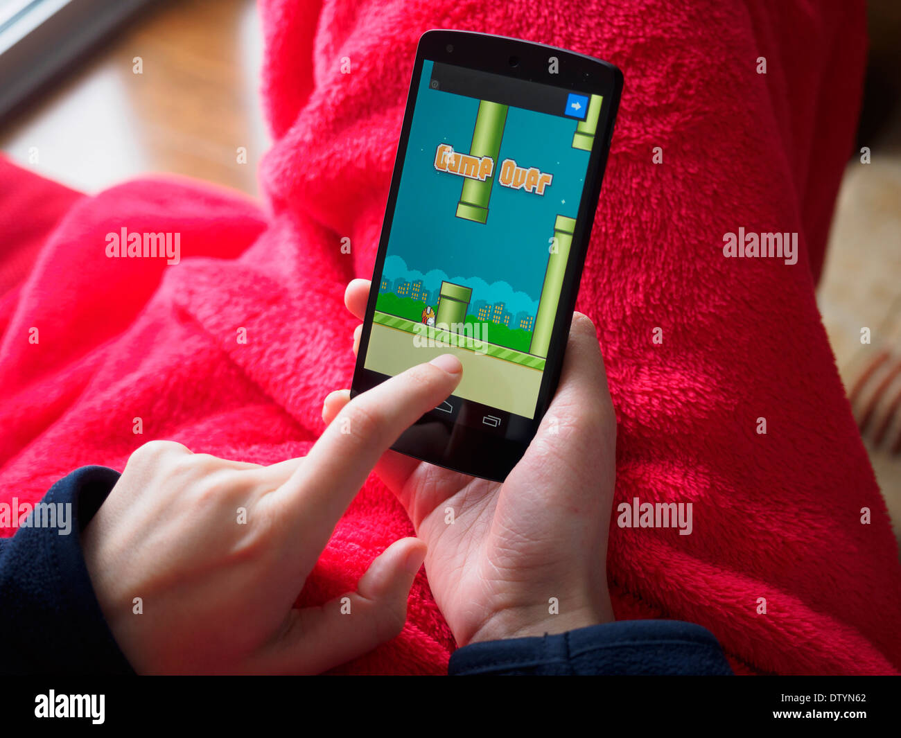 Cerca de la persona que juega Dong Nguyen's video juego Flappy pájaro sobre un smartphone Foto de stock