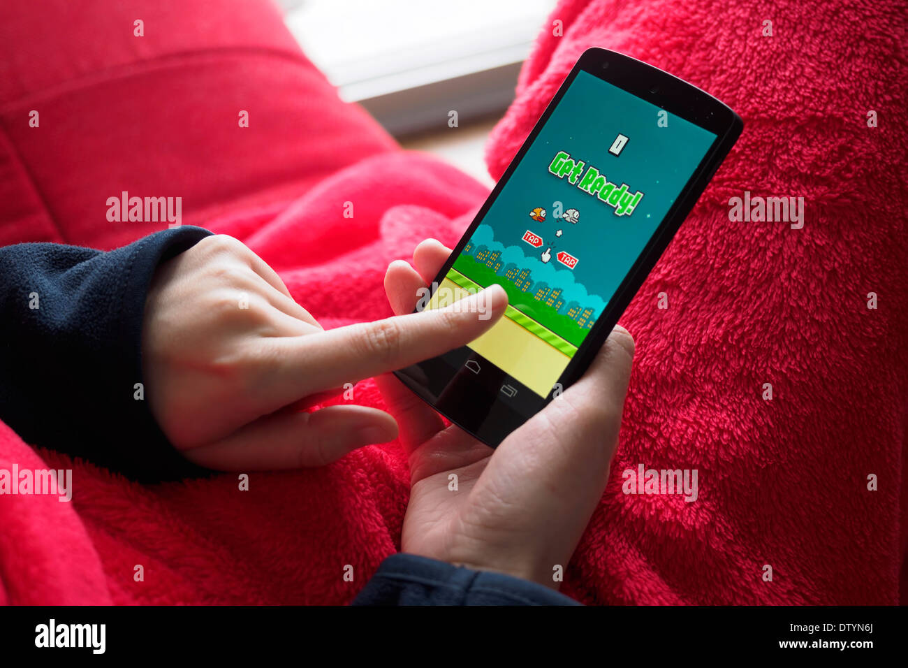 Cerca de la persona que juega Dong Nguyen's video juego Flappy pájaro sobre un smartphone Foto de stock