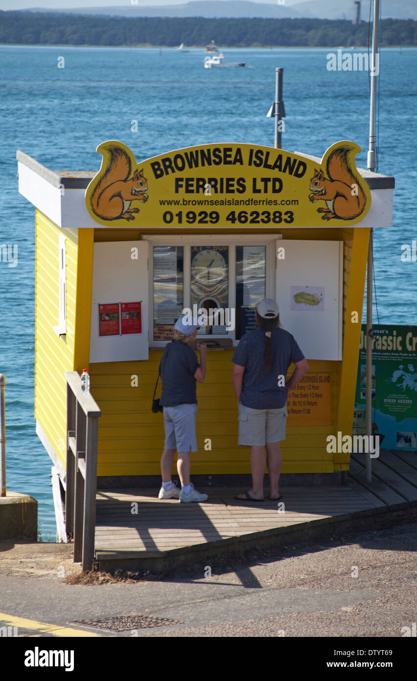 Dos personas comprando billetes en islas Brownsea Ferries Ltd quiosco en bancos de arena en septiembre Foto de stock