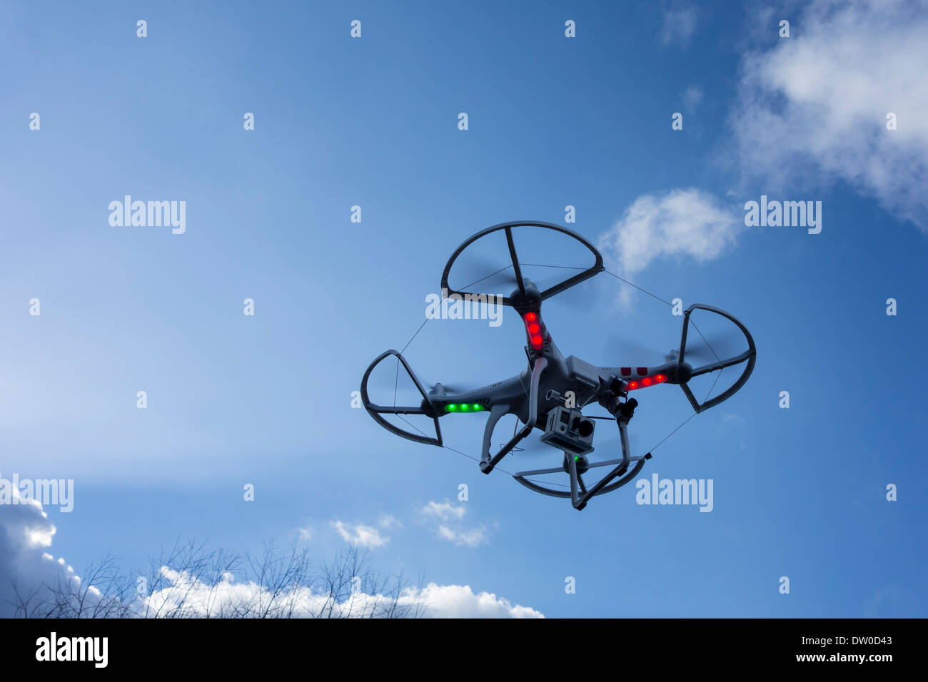 Miniatura drone / vehículo aéreo no tripulado / UAV equipado con cámara en vuelo contra el cielo azul con nubes Foto de stock