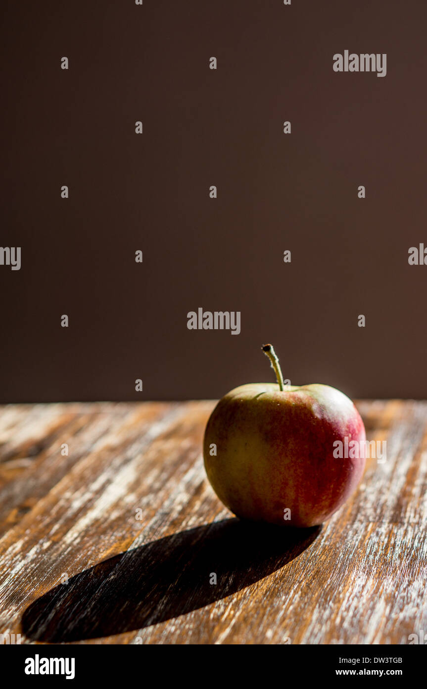 Una solitaria manzana en una tabla con un fondo liso Foto de stock