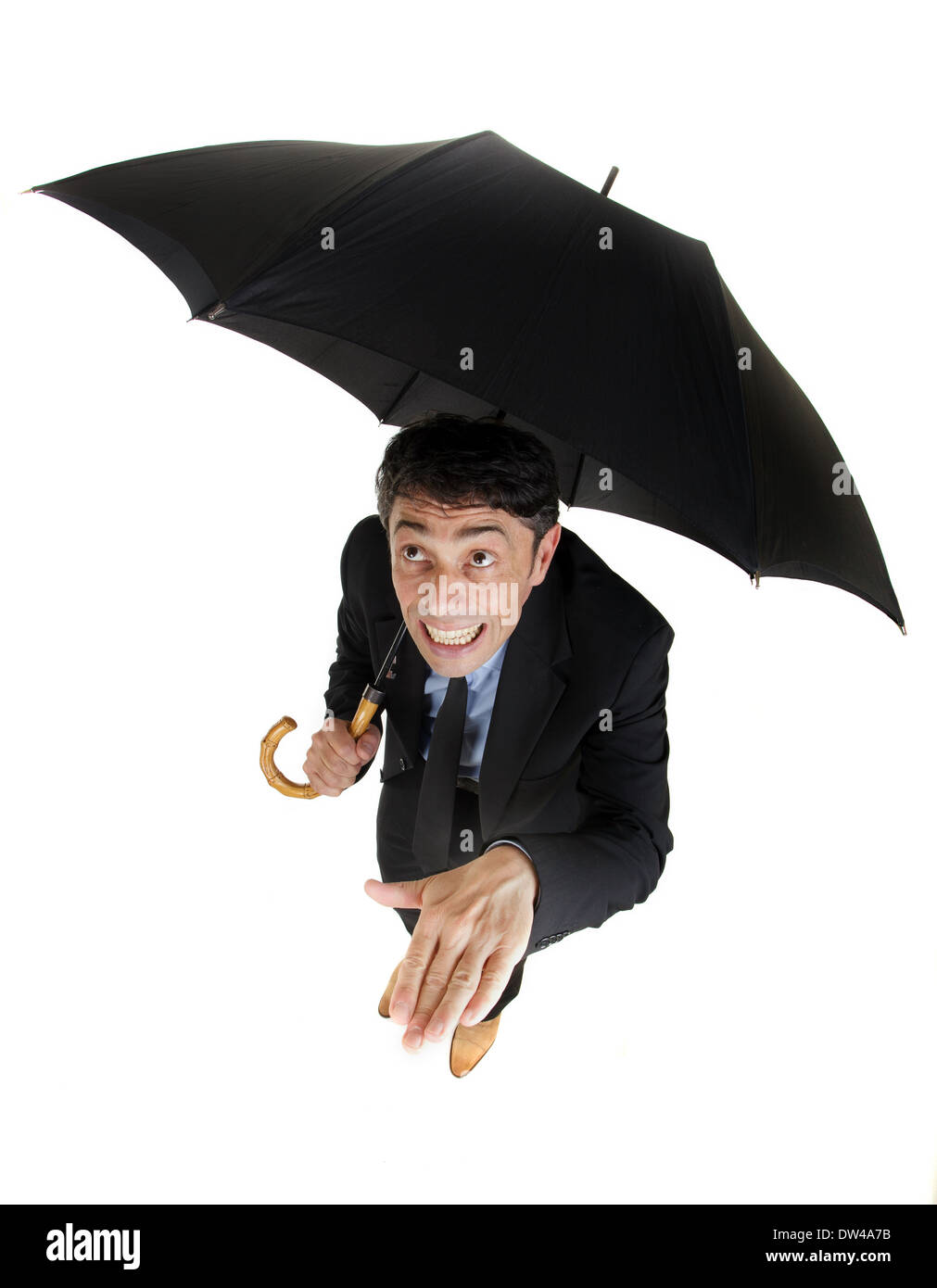 Humor un alto ángulo de longitud completa retrato de un empresario refugiarse bajo su paraguas comprobando la lluvia Foto de stock