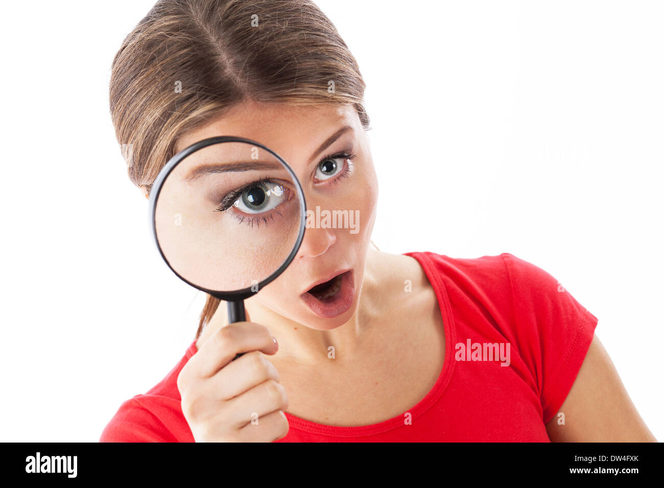 Chica busca a través de una lupa y mirando sorprendido, aislado en blanco Foto de stock