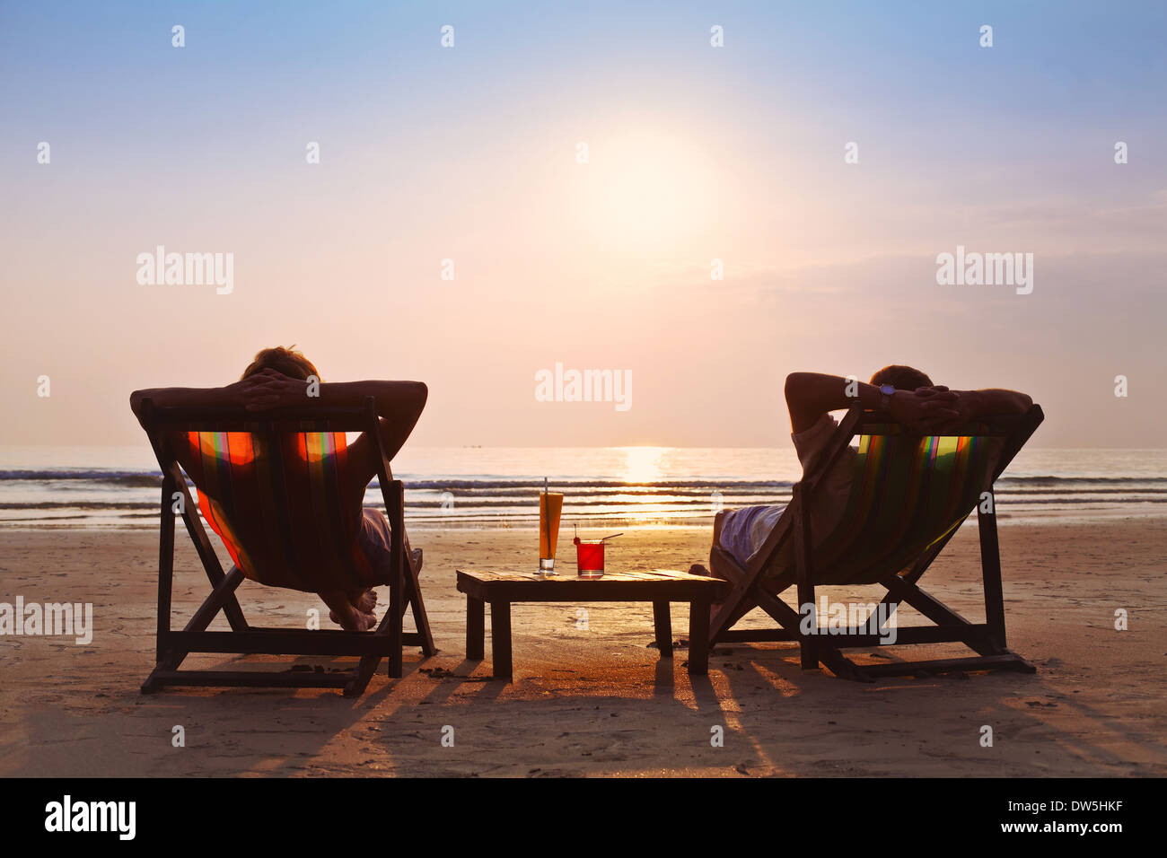 Feliz pareja disfrutar del atardecer en la playa Foto de stock