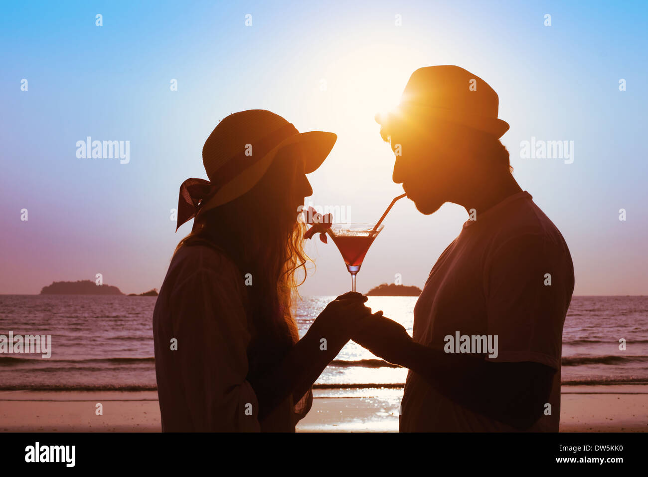 Compartir el placer, pareja de beber cócteles en la playa Foto de stock