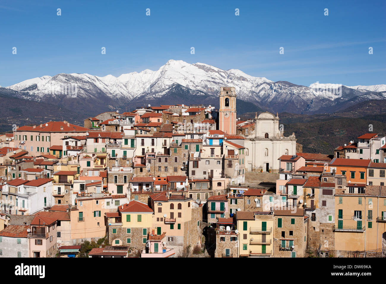 VISTA AÉREA. Pueblo medieval encaramado con los Alpes nevados en el horizonte. Perinaldo, Provincia de Imperia, Liguria, Italia. Foto de stock