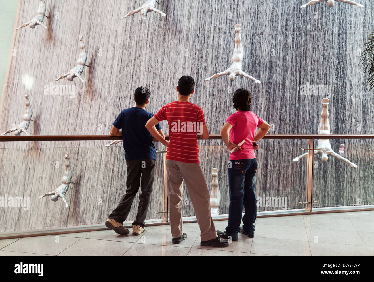 Tres adolescentes locales chicos mirando la cascada en el centro comercial Dubai Mall, Dubai, EAU, Emiratos Arabes Unidos, Oriente Medio Foto de stock