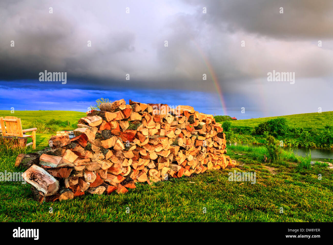 Pila de leña a un patio con arco iris en el fondo Foto de stock