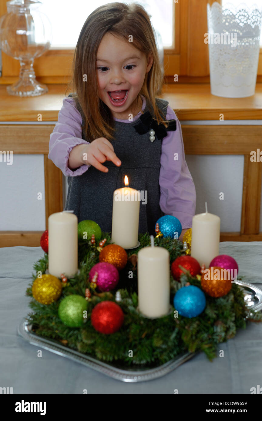 Chica disfrutando la primera vela en la corona de adviento Foto de stock