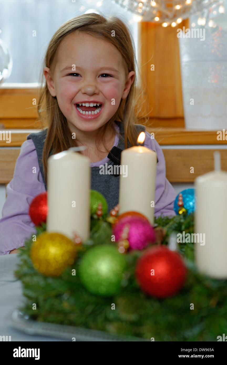 Chica disfrutando la primera vela en la corona de adviento Foto de stock