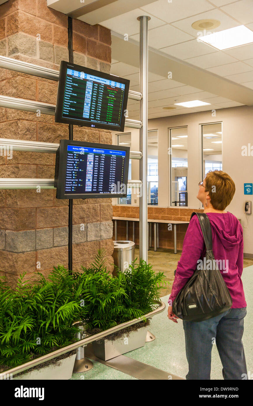 Mujer mirando una de las pantallas de llegada y de salida en el Aeropuerto Internacional de Pensacola en Pensacola, Florida Foto de stock