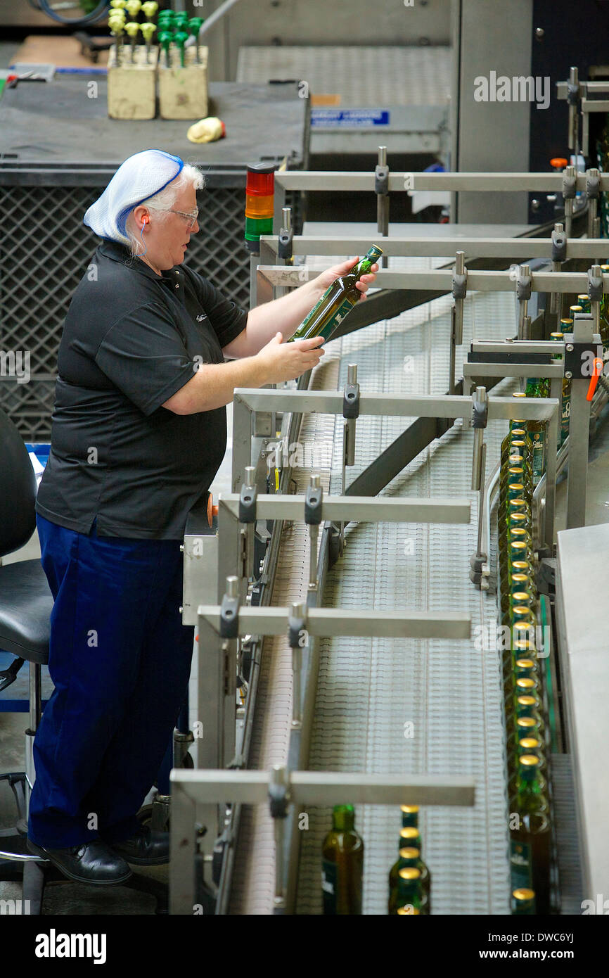 Un trabajador de producción que comprueba la calidad de las botellas de