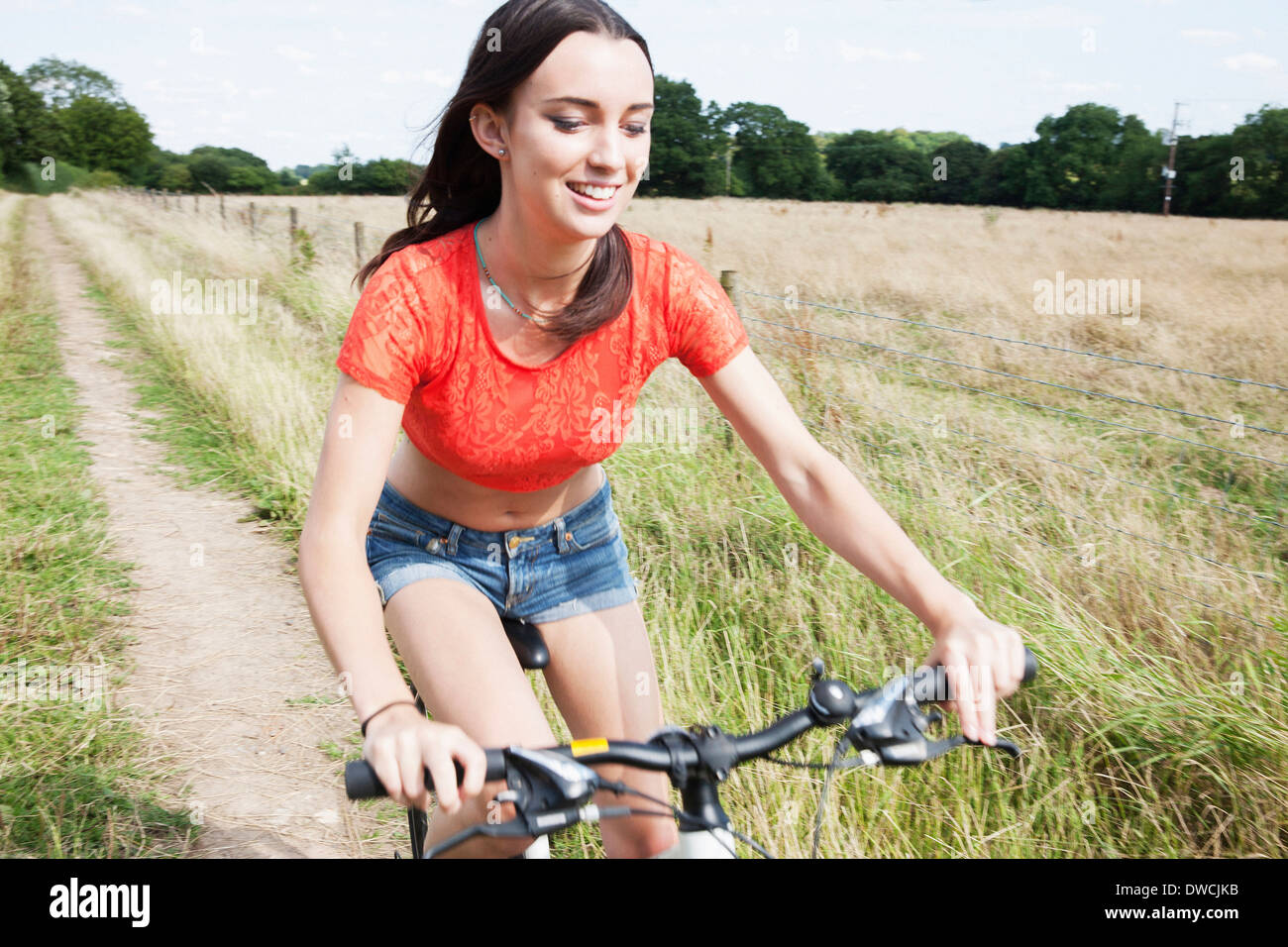 Mujer joven ciclismo en pista de tierra en el campo Foto de stock