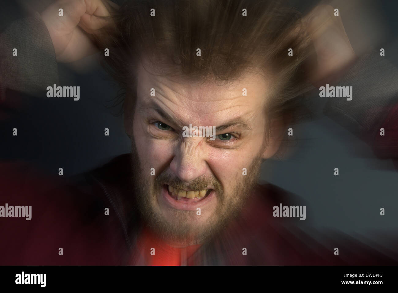 Un hombre enojado con un mal genio desgarrando su cabello. Foto de stock