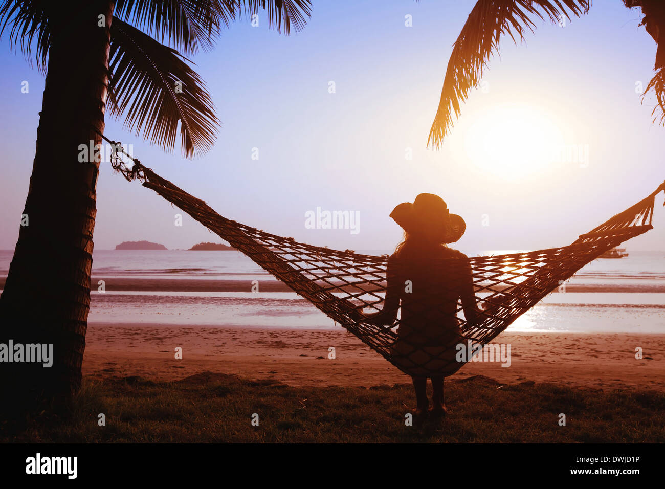 Relajarse en una hamaca al atardecer en la playa del paraíso Foto de stock