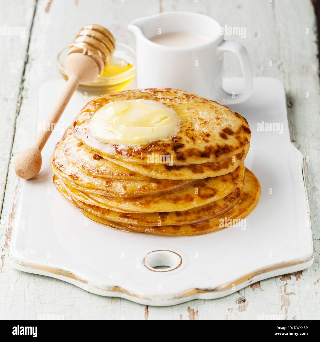 Pila de pequeñas tortitas con mantequilla y miel Foto de stock