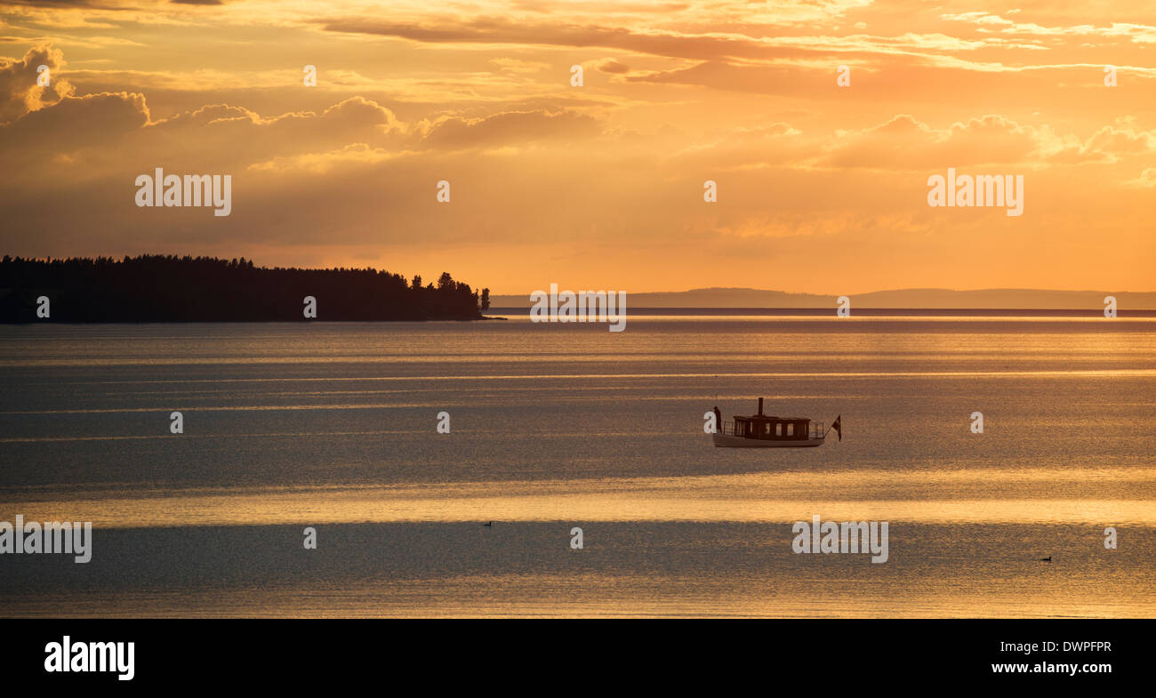 La tranquila noche de verano escena en Suecia. Silueta de la pequeña lancha en el lago Vattern al atardecer. Foto de stock