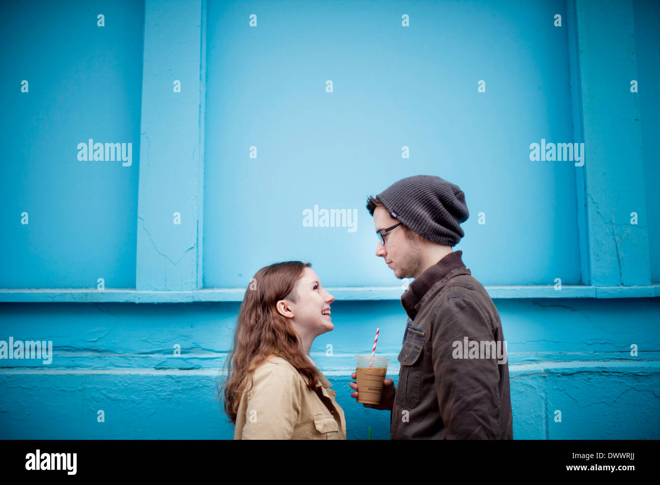 Estados Unidos, Massachusetts, pareja joven cara a cara, pared azul en segundo plano. Foto de stock