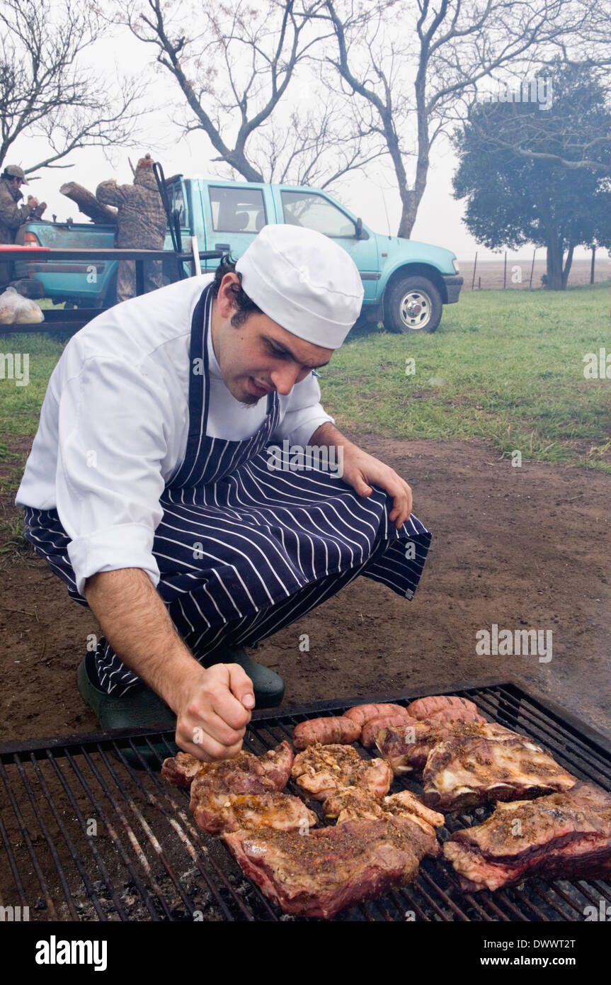 Chef sazonador de carne cocinar en la parrilla sobre brasas en Jacana Lodge en la provincia de Río Negro, Argentina Foto de stock