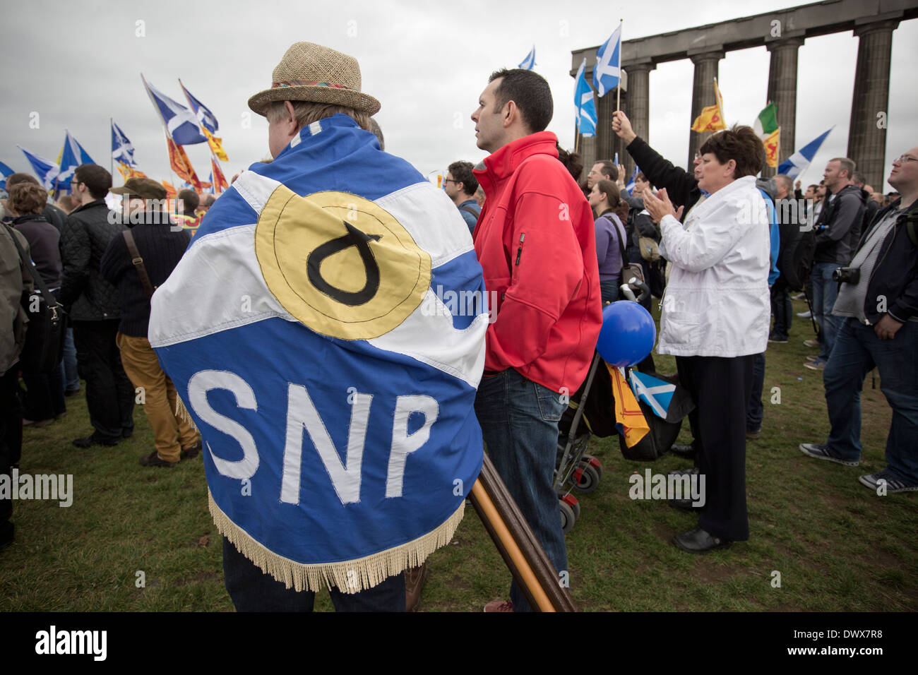 Un hombre con una bandera escocesa envuelto alrededor de él para escuchar discursos sobre Calton Hill en Edimburgo, durante un pro-independencia de marzo Foto de stock