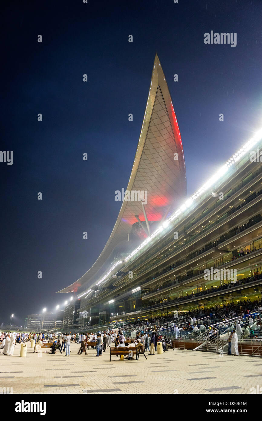 En la tribuna de espectadores y la reunión de carreras de caballos en el hipódromo de Meydan Al por la noche en Dubai, Emiratos Árabes Unidos Foto de stock