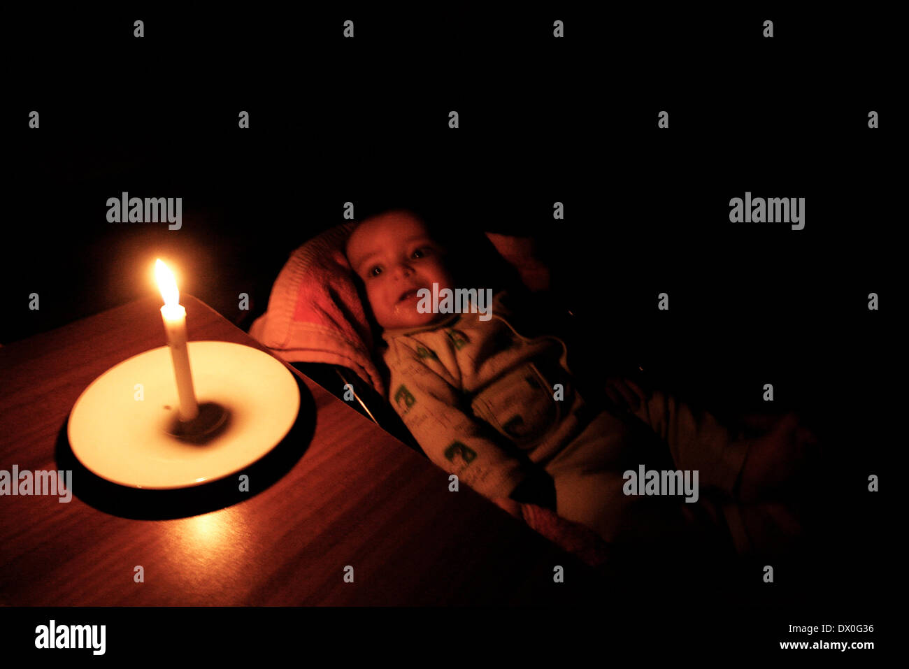 Gaza, Territorios Palestinos. 17 Feb, 2012. Un palestino Bebé sonriendo a la luz de las velas en su casa de familia durante los cortes de energía en el campamento de refugiados de Rafah, en el sur de la Franja de Gaza en marzo 15, 2014. La Franja de Gaza la única central eléctrica dejó de generar electricidad en sábado, provocando apagones en todo el territorio después de quedarse sin combustible, dijeron las autoridades. Gaza carece de mucha infraestructura civil básica y vive bajo un bloqueo egipcio-israelí significaba cortar el flujo de armas, sino que también frena las importaciones de combustible y materiales de construcción. (Crédito de la Imagen: © Abed Rahim Khatib/NurPhoto/ZUMAPR Foto de stock