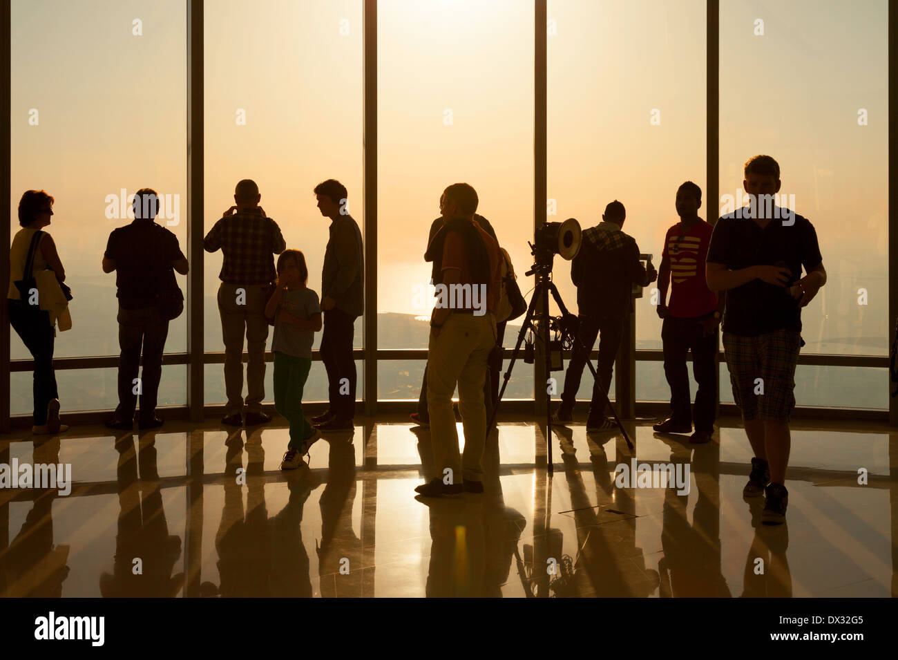Los turistas que ven la puesta de sol desde la plataforma de observación 'At the Top', edificio Burj Khalifa, Dubai, Emiratos Árabes Unidos. Siluetas de personas. Foto de stock