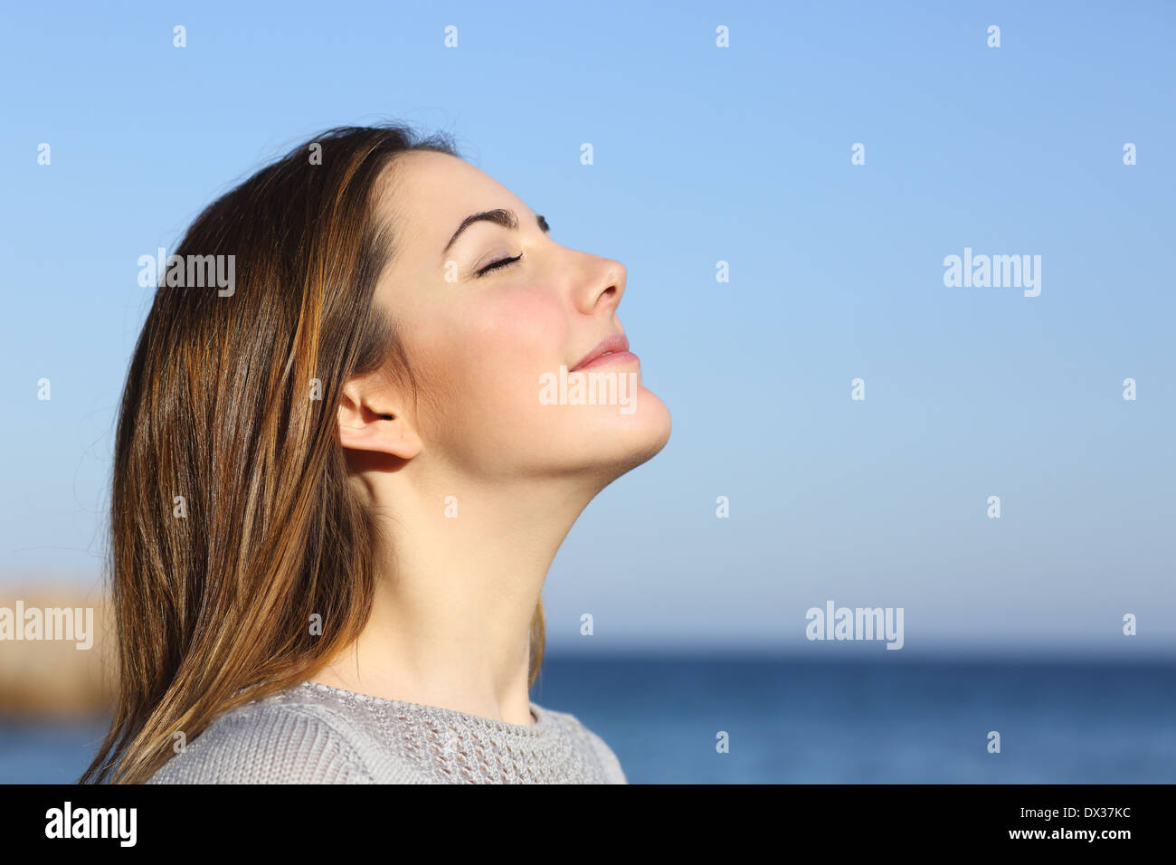 Perfil de mujer retrato profundo respirar aire fresco en la playa con el océano al fondo Foto de stock