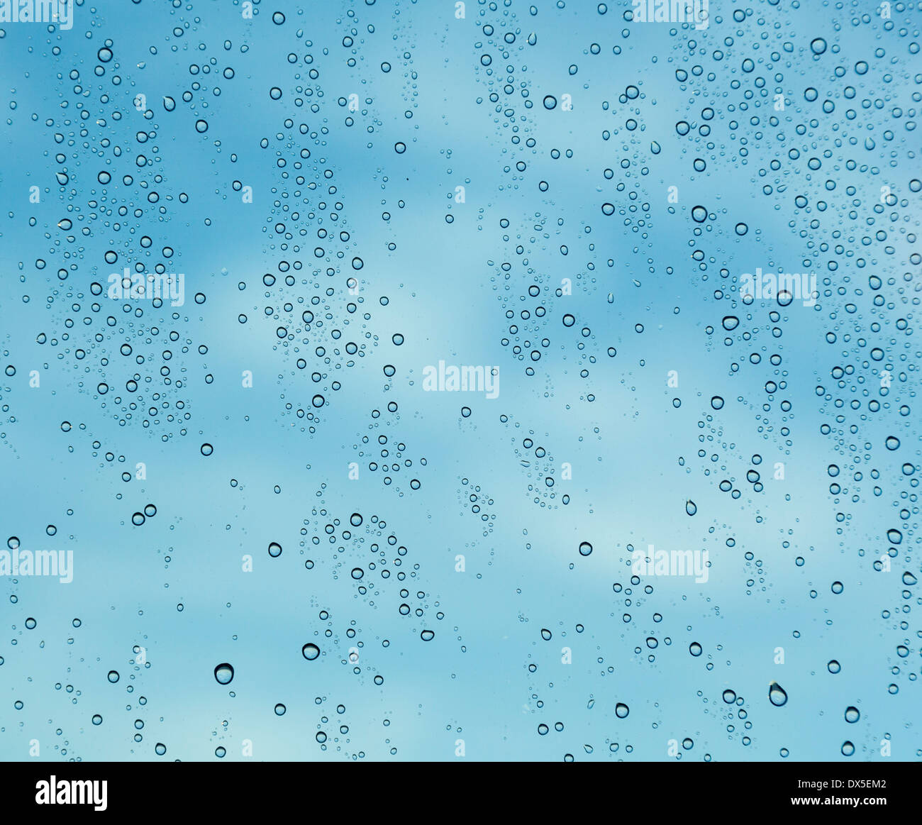 Resumen: El cielo y las nubes detrás de las gotas de lluvia en una ventana Foto de stock