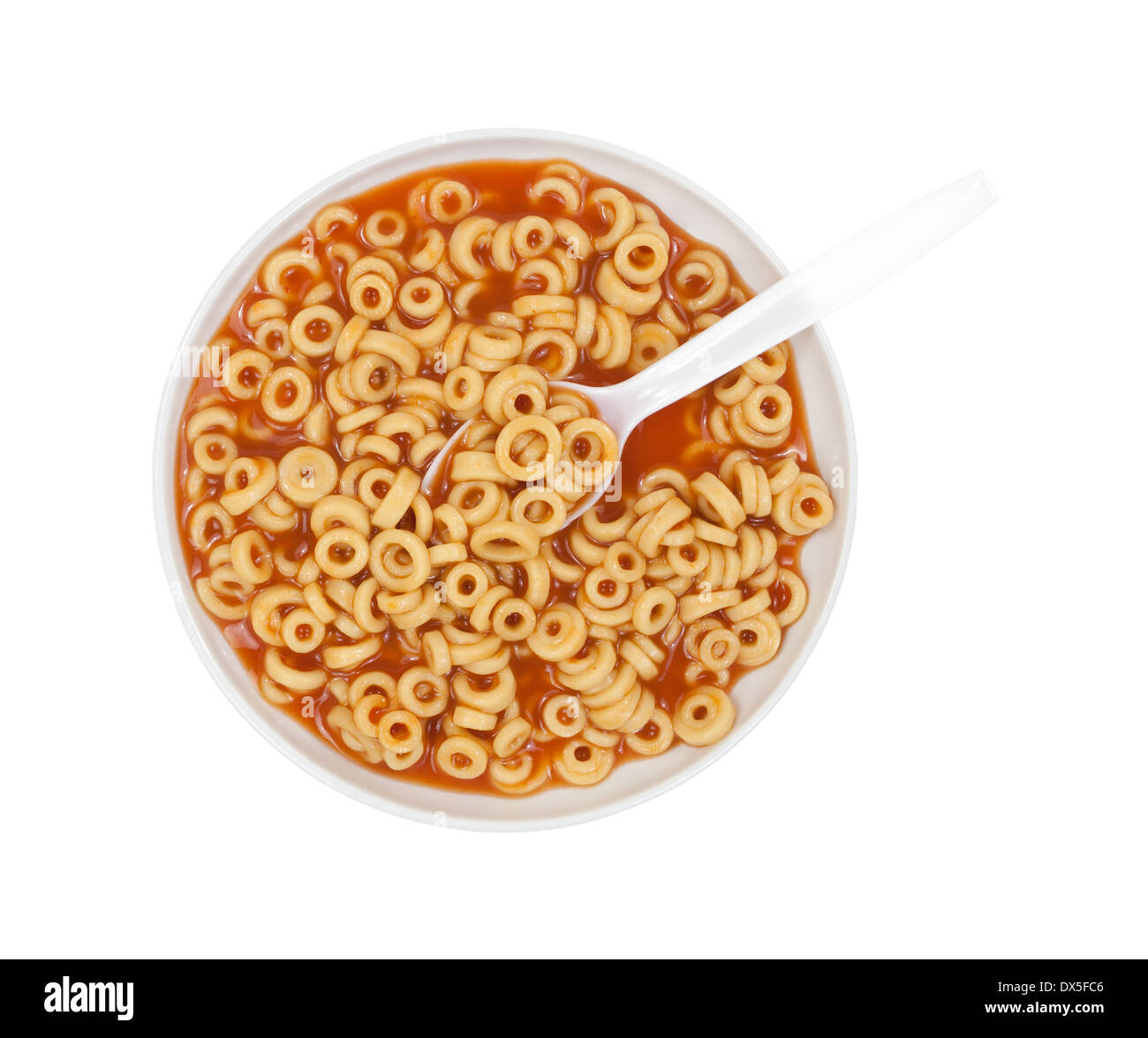 Vista superior de una porción de spaghetti redondo en un tazón con una cuchara de blanco. Foto de stock