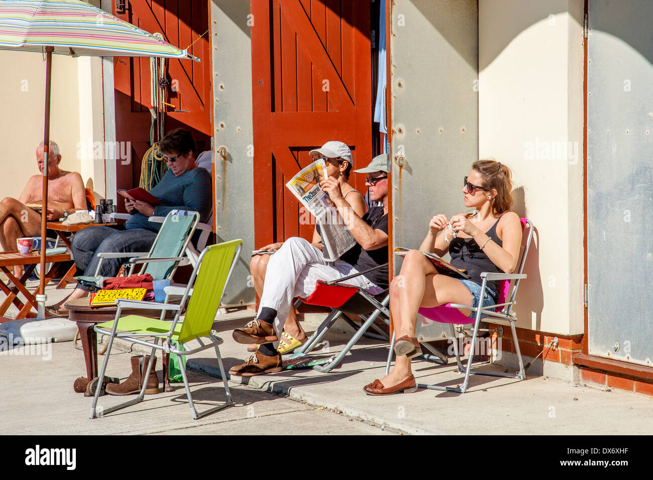 La gente relajándose fuera de cabañas de playa, Rottingdean, Sussex, Inglaterra Foto de stock