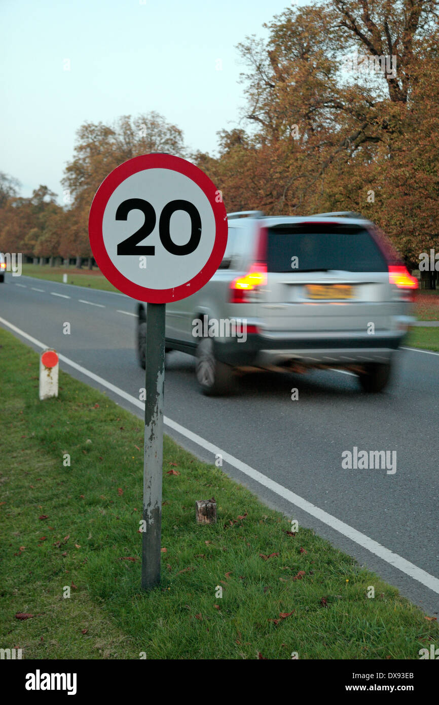 Gran coche pasando una señal de límite de velocidad de 20mph en Bushy Park, cerca de Kingston, en el Reino Unido. Foto de stock