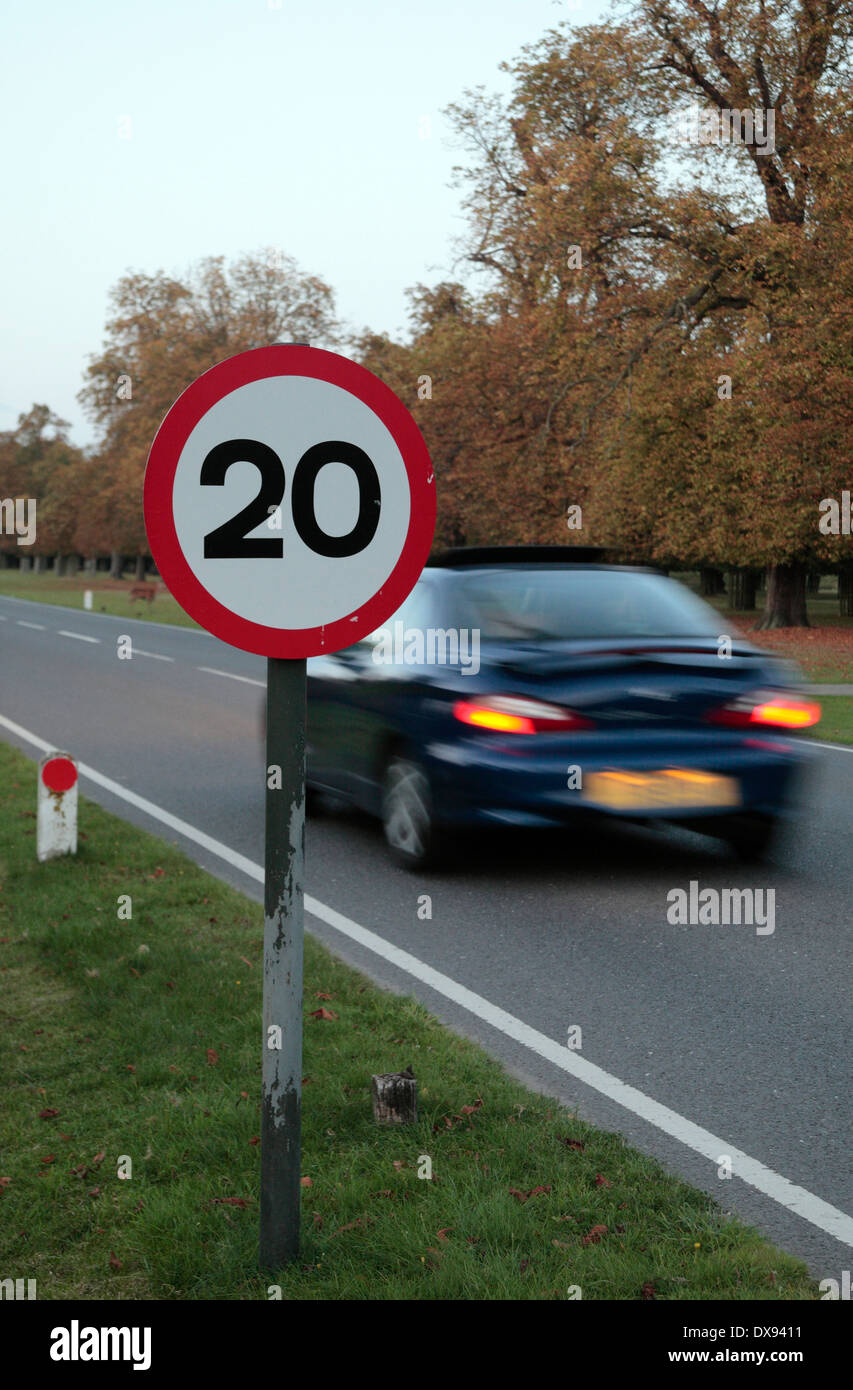 Coche pasando una señal de límite de velocidad de 20mph en Bushy Park, cerca de Kingston, en el Reino Unido. Foto de stock
