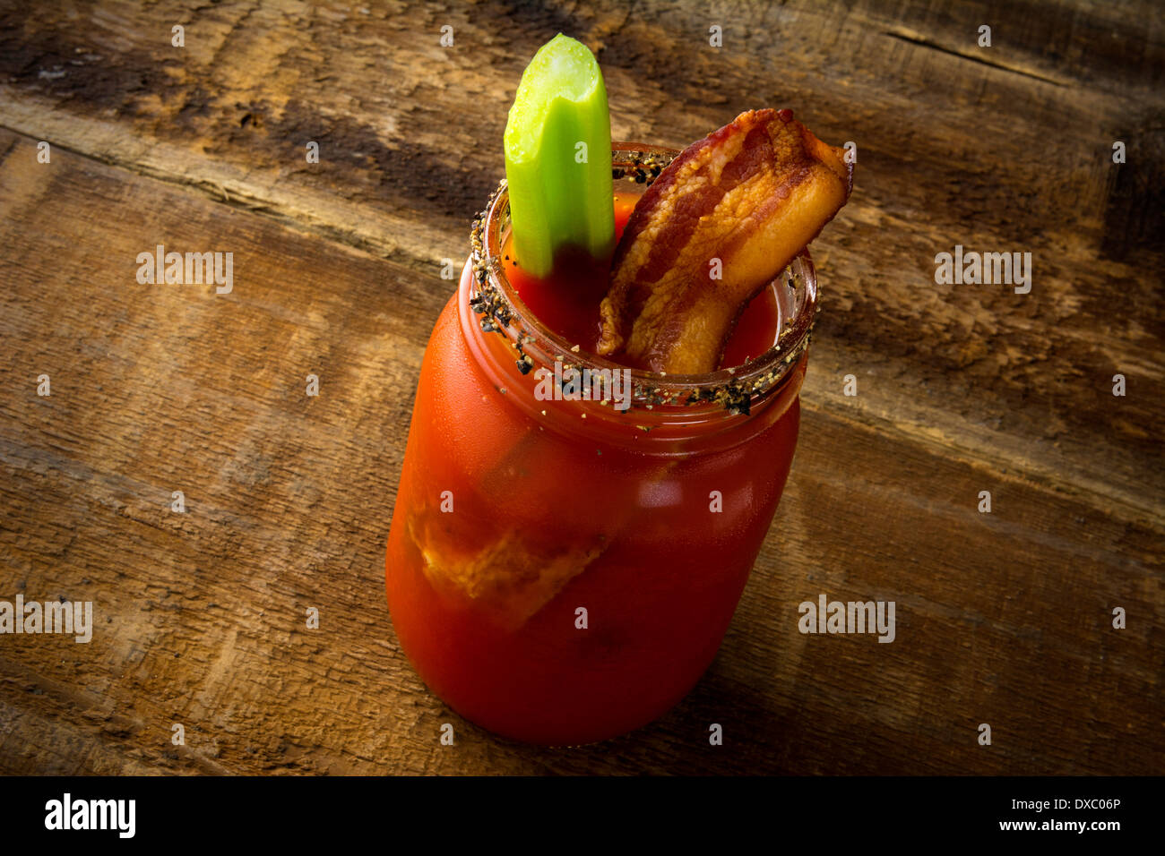 Mason jar Bloody Mary o César con bacon sobre fondo de madera Foto de stock