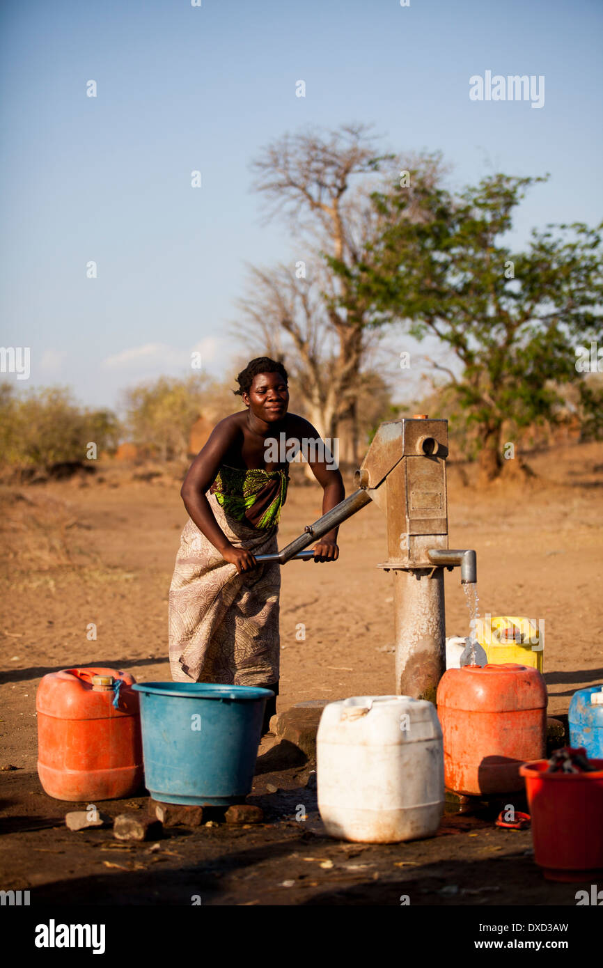 Mujer de África el bombeo de agua en un tubo de soporte Foto de stock