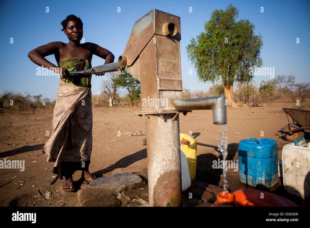 Mujer de África el bombeo de agua en un tubo de soporte Foto de stock