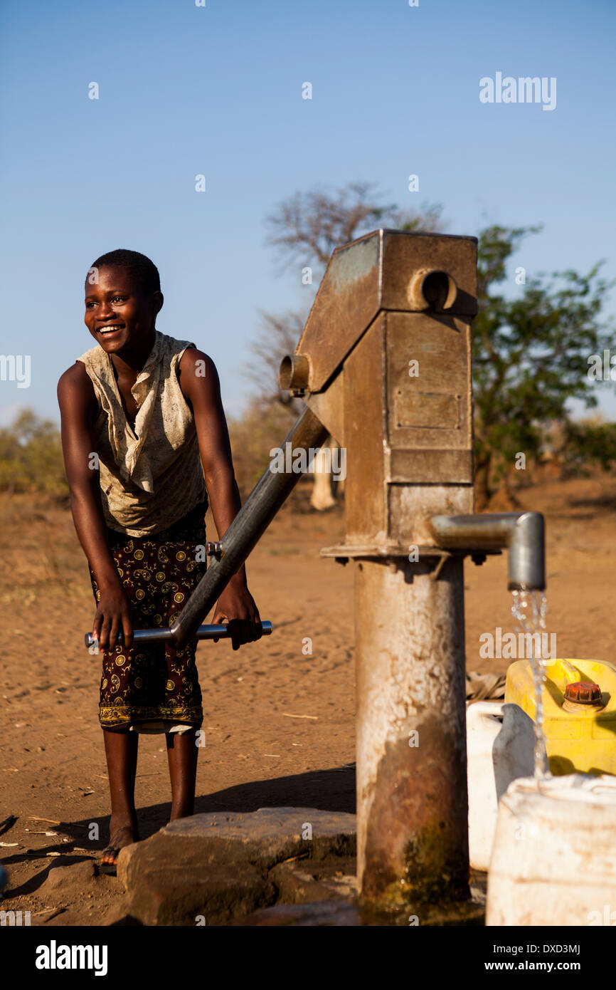 África niño recogiendo agua en un tubo de soporte Foto de stock