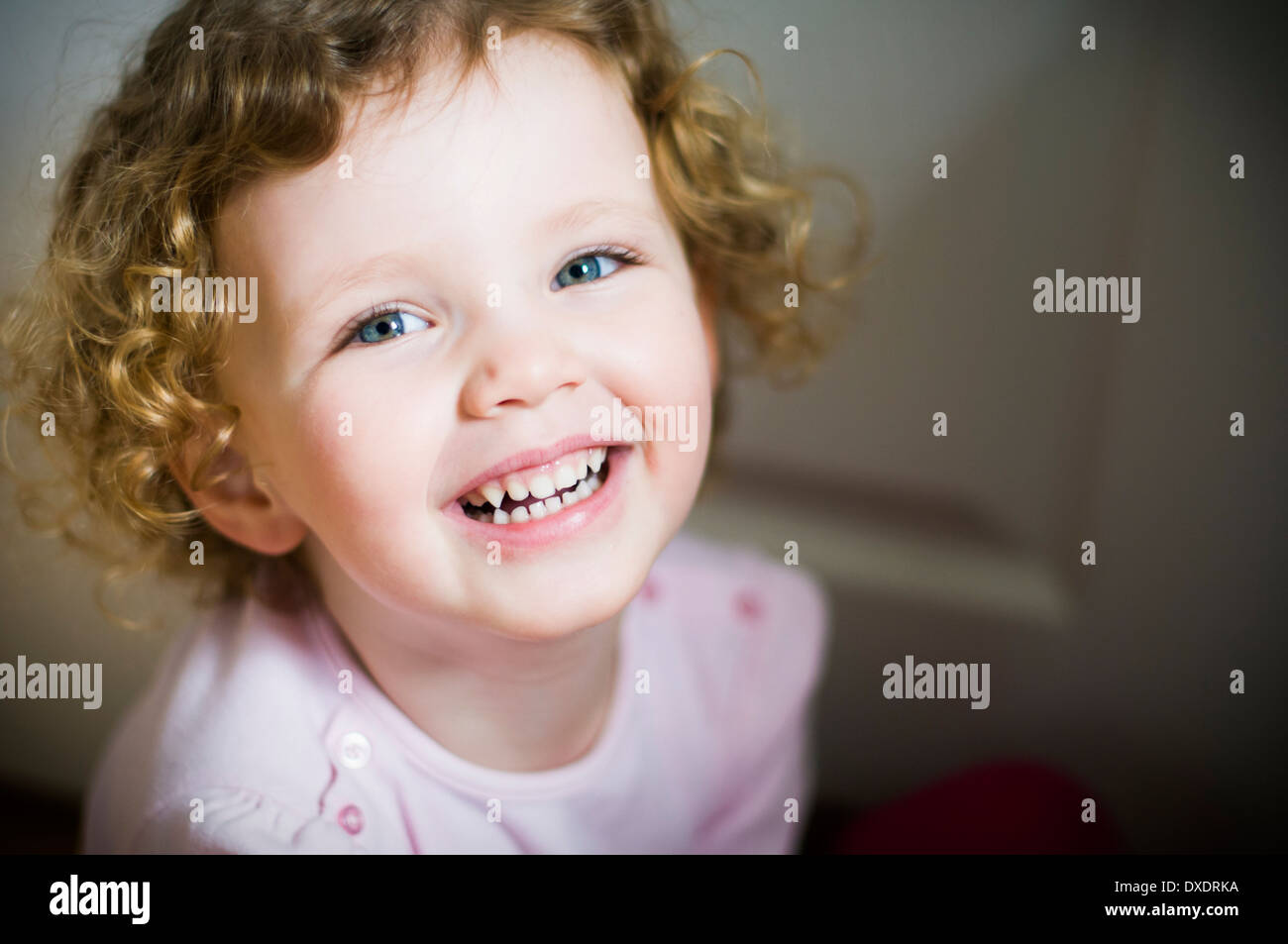 Adorable jovencita con el pelo rizado sonriendo y riendo Foto de stock