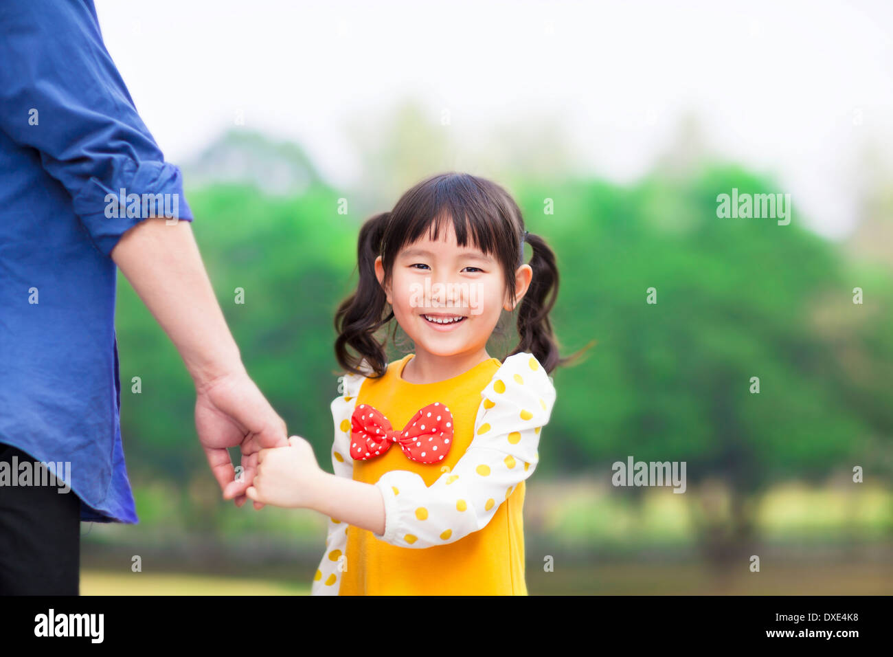 Linda chica asiática padre mantenga la mano en el parque Foto de stock