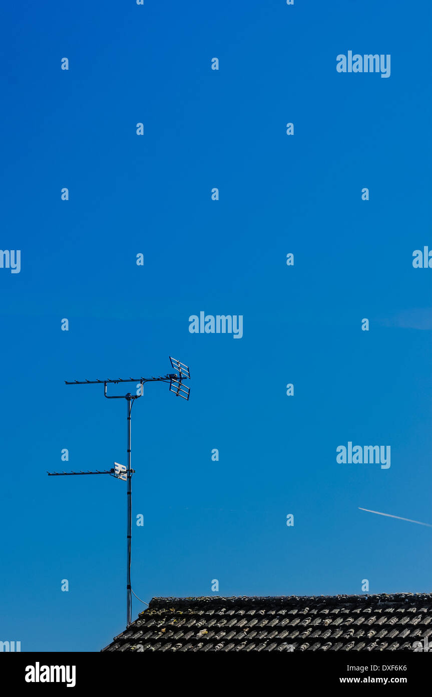 El viejo estilo de antena de televisión / La antena en la parte superior del techo de tejas negras principalmente contra el cielo azul. Foto de stock