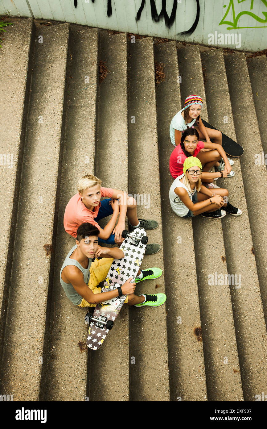Un grupo de niños sentados en las escaleras exteriores, mirando hacia la cámara, Alemania Foto de stock
